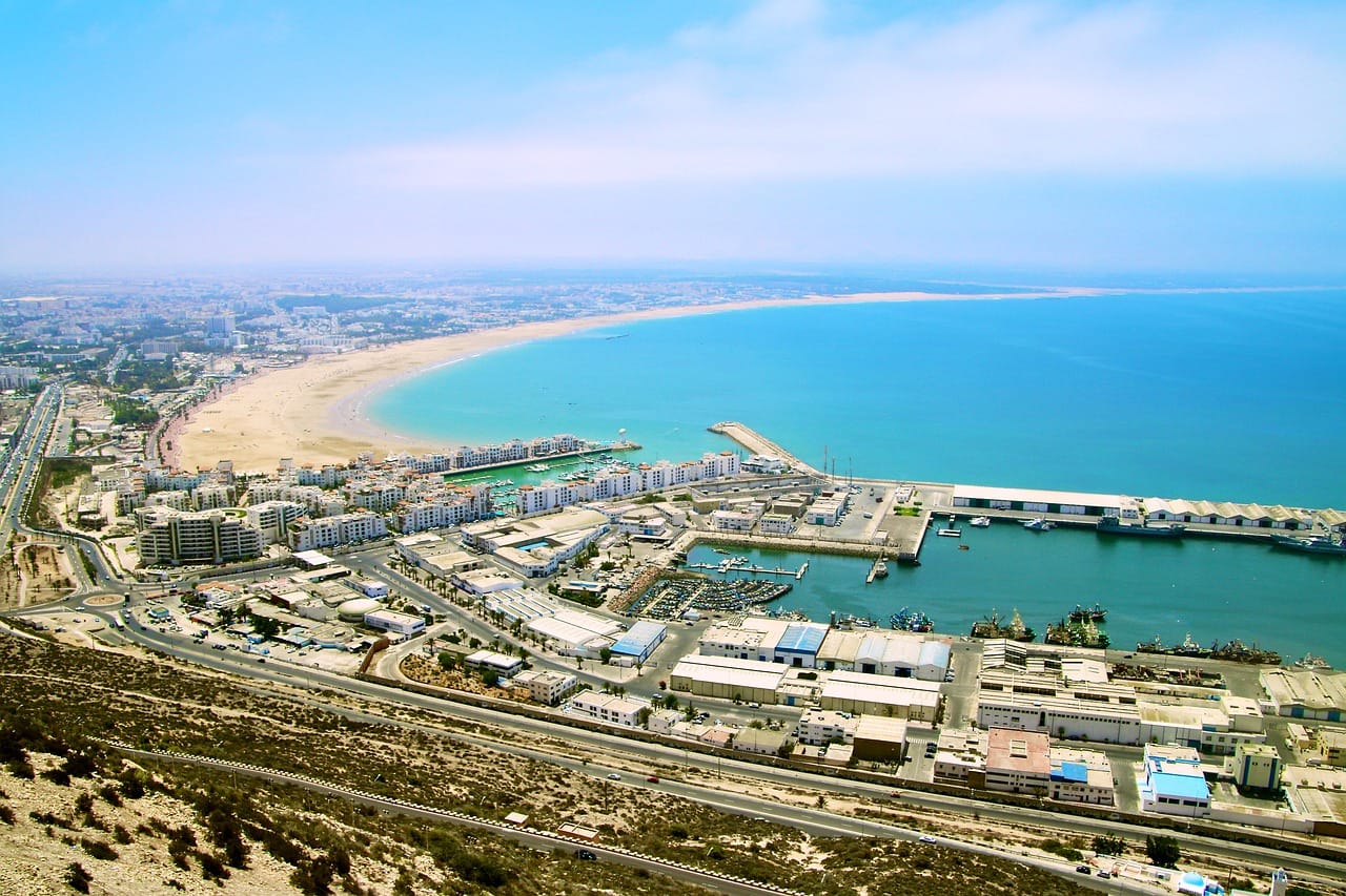 Tour da Agadir al deserto - Panorama Baia di Agadir e porto - Viaggio Organizzato in Marocco da Agadir 2027 Agadir 5 giorni Merzouga ed Essaouira deserto oceano - Essaouira barche blu porto UNESCO - Agadir Draa Merzouga Erg Chebbi 150m campo lusso